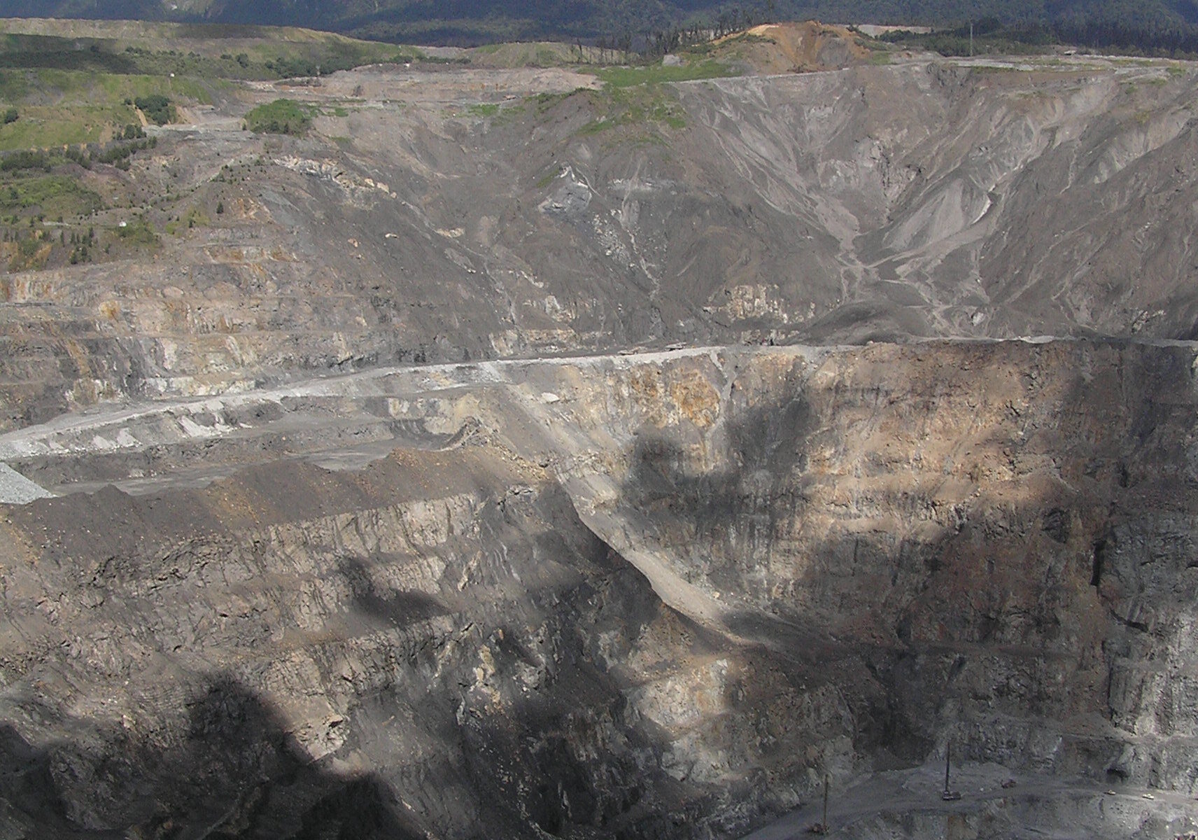 Perogera-Gold-Mine: Tiefer Gesteinstagebau in einer grünen gebirgigen Landschaft